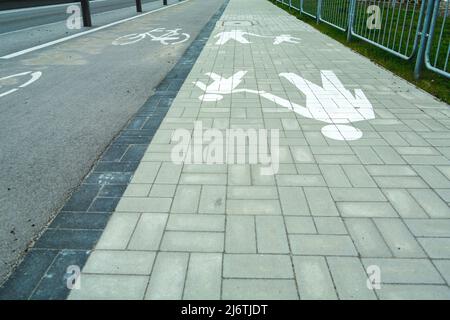 Radweg neben Fußweg und horizontalen Warnschildern Stockfoto