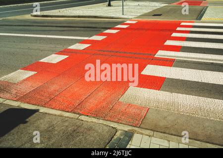 Rote Fahrradstraße neben Fußgängerüberweg Stockfoto