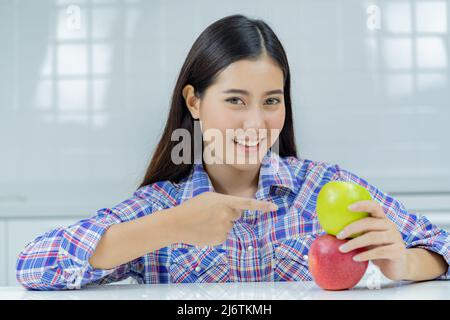 asiatische Frau glücklich hält grünen Apfel und roten Apfel. Stockfoto