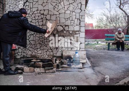 12. April 2022, Bucha, Ukraine: Ein Mann kocht sein Abendessen auf der Straße, weil es in der Stadt an Gas, Strom und Wasser mangelt. Bucha, eine Stadt am Rande der ukrainischen Hauptstadt Kiew, wurde etwa einen Monat lang von russischen Soldaten kontrolliert. Ihre Befreiung am 31. März enthüllte einige der grausamsten Gräueltaten, die russische Soldaten während der Besatzung verübt hatten. Gebäude wurden zerstört und Häuser geplündert. In Bucha Straßen, Gebäuden und Massengräbern wurden Leichen gefunden. (Bild: © Rick Mave/SOPA Images via ZUMA Press Wire) Stockfoto