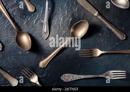 Besteckmuster. Löffel, Gabeln und Messer. Modernes Geschirr auf schwarzem Schieferhintergrund, von oben geschossen, eine flache Laie Stockfoto