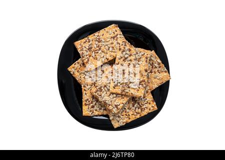 Haufen Getreidekekse mit Sesam auf einem schwarzen Teller isoliert auf weißem Hintergrund. Draufsicht Stockfoto