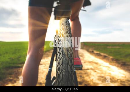 Nahaufnahme eines Fahrradreifenschutzschalters. Rückansicht eines Radfahrrads auf einer Landstraße bei sonnigem Tag. Radfahren an einem schönen sonnigen Tag. Fahrradtouren Stockfoto