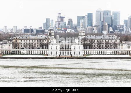 Blick auf das Queens House und Canary Wharf vom Greenwich Park in London im Winterschnee Stockfoto