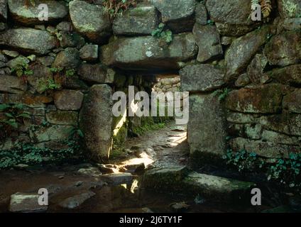 Sehen Sie südöstlich des Eingangsdurchgangs und des megalithischen Portals einer unterirdischen Kammer aus der Eisenzeit im alten Dorf Carn Euny, West Penwith, Cornwall, England, Großbritannien. Stockfoto