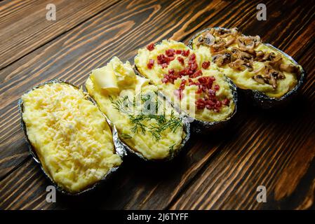 Gebackene Kartoffel in Folie mit Snacks Stockfoto