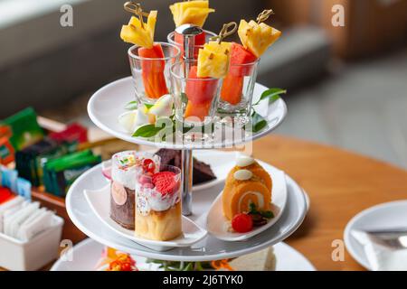 Mixed tropical fruit skewers, cakes, cookies, afternoon tea set for two persons Stockfoto