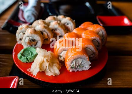 Sushi-Restaurant-Menü, köstliche japanische traditionelle Meeresfrüchte. Gourmet-Maki-Rolle mit Tamago-Omelette, chuka und Frischkäse, mit Lachs bedeckt, Serv Stockfoto