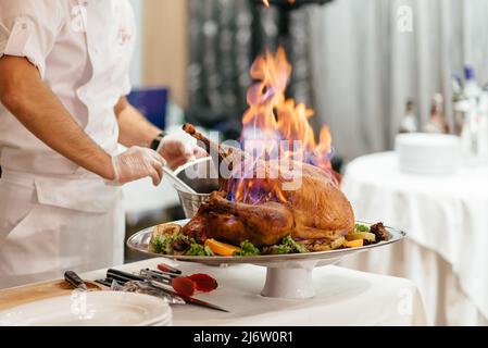 Gebratener, geschnittener Weihnachtsschinken auf Teller mit Gabel, Messer und festlicher Dekoration auf dunklem rustikalem Hintergrund, Draufsicht, Bordüre Stockfoto