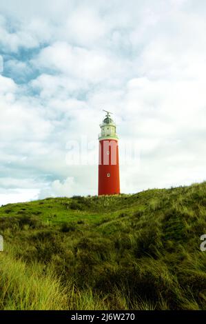 Leuchtturm Texel auf Green Grass Hill gegen blauen Wolkenhimmel. Nationalpark Duinen van Texel, Insel Texel, Niederlande Stockfoto