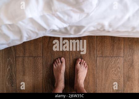 Barfuß-Mann, der vor dem Bett steht, Draufsicht Stockfoto