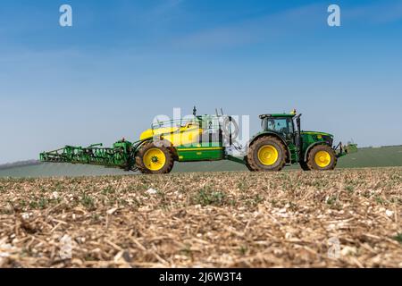 Besprühen von Ackerpflanzen auf den Yorkshire Wolds in der Nähe von York mit einem John Deere 6215 Traktor und einem gezogenen John Deere R952i Sprühgerät. Stockfoto