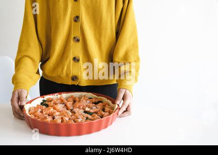 Frau kocht Quiche mit Lachs und Spinat. Kochen. Stockfoto