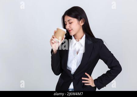Unternehmer ziemlich junge asiatische Frau, schöne attraktive asiatische Geschäftsfrau trägt schwarzen Anzug Lächeln Gefühl glücklich hält Kaffee Tasse mit Kopie s Stockfoto