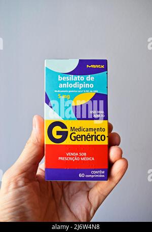 RIO DE JANEIRO, BRASILIEN - 21. APRIL 2022: Hand hält eine Schachtel mit (generischem) Amlodipin-Besylat, einem Medikament zur Kontrolle von Bluthochdruck Stockfoto