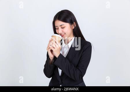 Unternehmer ziemlich junge asiatische Frau, schöne attraktive asiatische Geschäftsfrau trägt schwarzen Anzug Lächeln Gefühl glücklich hält Kaffee Tasse mit Kopie s Stockfoto