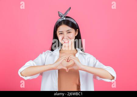 Hübsche Frau emotional positiv zeigt Herzform auf ihren Händen. Stockfoto
