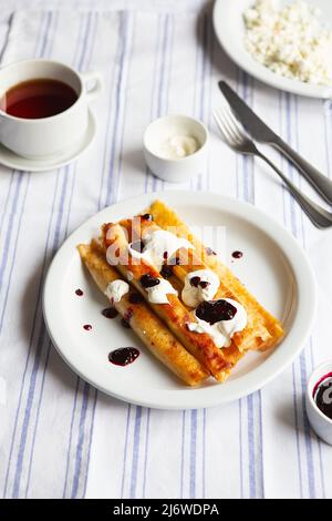 Gebratene Gefüllte Pfannkuchen Verbliesen. Russische dünne Pfannkuchen mit Quark, saurer Rahm und Marmelade. Gesundes traditionelles Frühstück.leckere gefüllte Pfannkuchen c Stockfoto