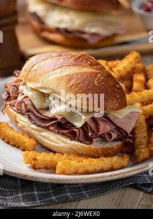 U-Boot-Sandwich mit heißem Schinken und Käse und Pommes auf einem Teller Stockfoto