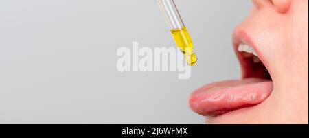 Zungenöl Pipette. Pflanzliche alternative Medizin und Nahrungsergänzungsmittel Frau, die CBD Hanföl Tropfen im Mund von Tropf. Medizinisches Cannabisöl Stockfoto