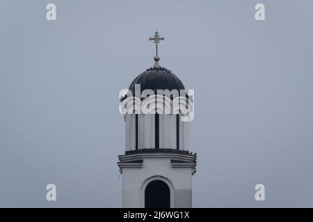 Mehrere Tauben ruhen während eines trüben bewölkten Tages auf dem Dach des Kirchturms Stockfoto