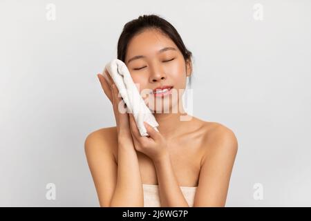 Junge asiatische Dame reiben ihr Gesicht mit Handtuch Stockfoto