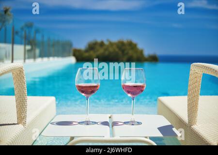 Zwei Gläser mit Cocktails auf dem Tisch zwischen Liegestühlen, Sonnenliegen am Pool, Meer und blauer Himmel im Hintergrund. Sommerferien, Entspannung, Unterkunft Stockfoto