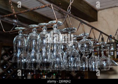 Viele Glaskelche hängen über der Bar. Leere Gläser Stockfoto