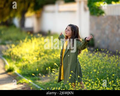 Schönes Mädchen im Freien genießen die Natur. Schöne Teenager-Model-Mädchen in einem grünen Regenmantel, Freiheit Konzert Stockfoto