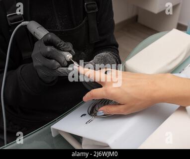 Manikurist entfernt Nagellack verwendet die elektrische Maschine der Nagelfeile während der Maniküre Stockfoto