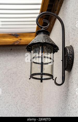 An der Wand ist eine eiserne schwarze Lampe angebracht. Lampe an der Wand aus der Nähe Stockfoto