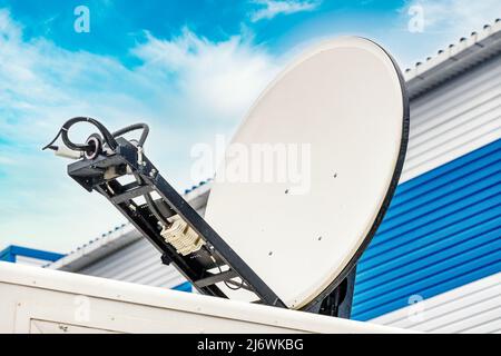 Die mobile runde Satellitenschüssel ist nach Himmel gerichtet. Bereitstellung von Kommunikationsgeräten. Hintergrund Stockfoto