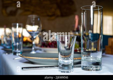 Tabelleneinstellung. Glas, Stapel, Schüsseln und Gabel auf dem Tisch. Besteck auf einer weißen Tischdecke Stockfoto