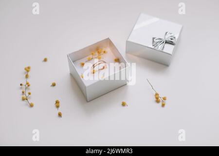 Box mit goldenem Verlobungsring auf Blumenhintergrund, Draufsicht. Hochzeit, Heiratsantrag Konzept. Stockfoto