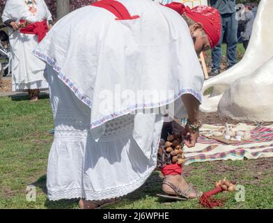 Eine Tänzerin der mexikanischen Tanzgruppe von Calpulli passt das hölzerne Schlaginstrument auf ihrem Knöchel während der Azteken-Feier an. In NYC Stockfoto