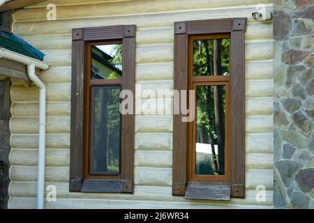 Teil eines Holzhauses. Fenster mit Holzrahmen aus nächster Nähe. Stockfoto