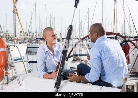 Ein paar Jungs in blauen Hemden plaudern auf einer privaten Segelyacht im Seehafen Stockfoto