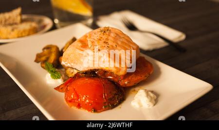 Lachsscheibe mit Tomatenspinon und Kokosnusssoße auf einem weißen Teller köcheln lassen Stockfoto