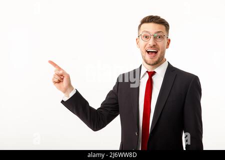 Ein junger Geschäftsmann in einem Geschäftsanzug weist auf Copyspace hin. Stockfoto