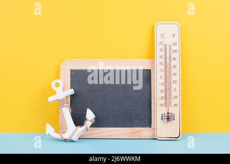 Leere Tafel mit Thermometer und Anker, Hintergrund im Urlaub, Sommerurlaub, heißes Wetter, Umweltproblem Stockfoto
