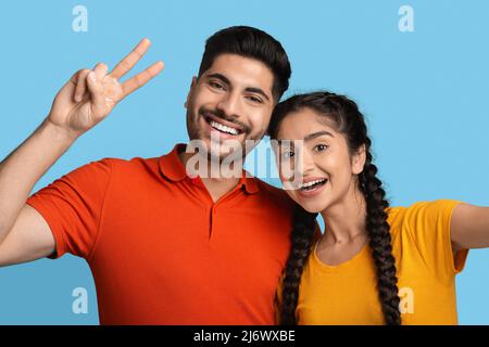 Happy Young Arabic Couple Taking Selfie Together Over Blue Background Stockfoto
