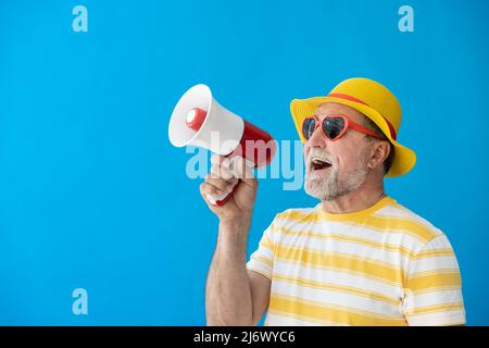 Glücklicher älterer Mann, bereit zu reisen. Person, die über Lautsprecher schreit. Sommerurlaub und Urlaubskonzept Stockfoto