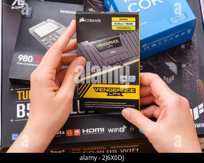 Tambow, Russische Föderation - 07. April 2022 Eine Frau hält eine Box mit einem Corsair DDR4-Speicher über andere Boxen mit brandneuen Komponenten Stockfoto