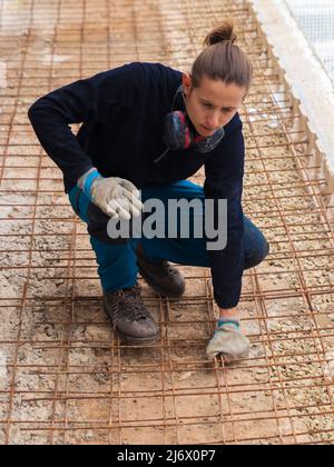 Arbeiter, der auf der Baustelle ein Gitter für Betonverstärkung auf den Boden legt Stockfoto