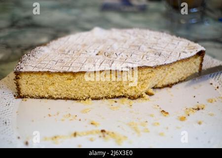 Ein hausgemachter Kuchen, der zur Hälfte als Dessert über einem Tisch gegessen wird Stockfoto