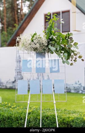 Hochzeitstafel, Mockup, EinladungsStaffelei, mit Platz für eine Inschrift, dekoriert mit frischen Blumen. Festliche Einrichtung, Kopierfläche. Weicher, selektiver Fokus. Stockfoto