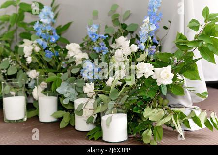 Hochzeitspresidium im Restaurant. Banketttisch für frisch Vermählte mit Blumen, Grün, Kerzen und Girlande-Ligths. Üppiges Blumenarrangement. Luxus-Weddi Stockfoto