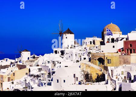 Oia, Santorini, Griechische Inseln, Griechenland - Kirche mit Kuppel, Windmühlen, Häusern und anderen weißen Gebäuden auf Klippen bei strahlendem Sonnenschein Stockfoto