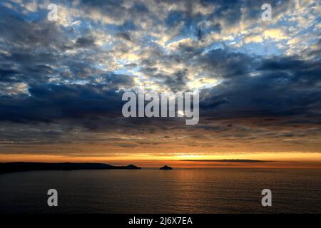 Die untergehende Sonne und der Abendhimmel an der Küste von North Cornwall bei Trevan Head in der Nähe von Port Quin. Blick auf das gesamte Headland, die Rumps und die Mouls. Stockfoto