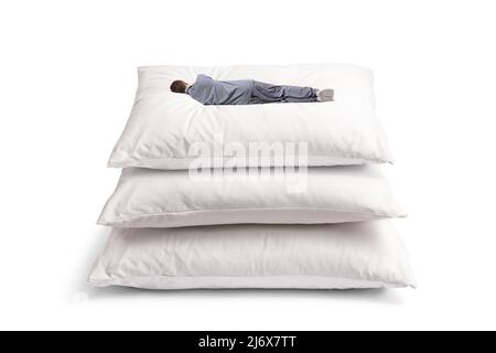 Rückansicht eines Mannes, der auf einem Haufen großer Kissen auf weißem Hintergrund schläft Stockfoto